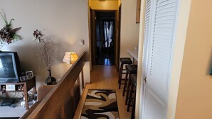 A hallway with a wooden bench, a TV on a stand, a lamp, and a patterned rug. - Stylish two bedroom Condo (Milwaukee)