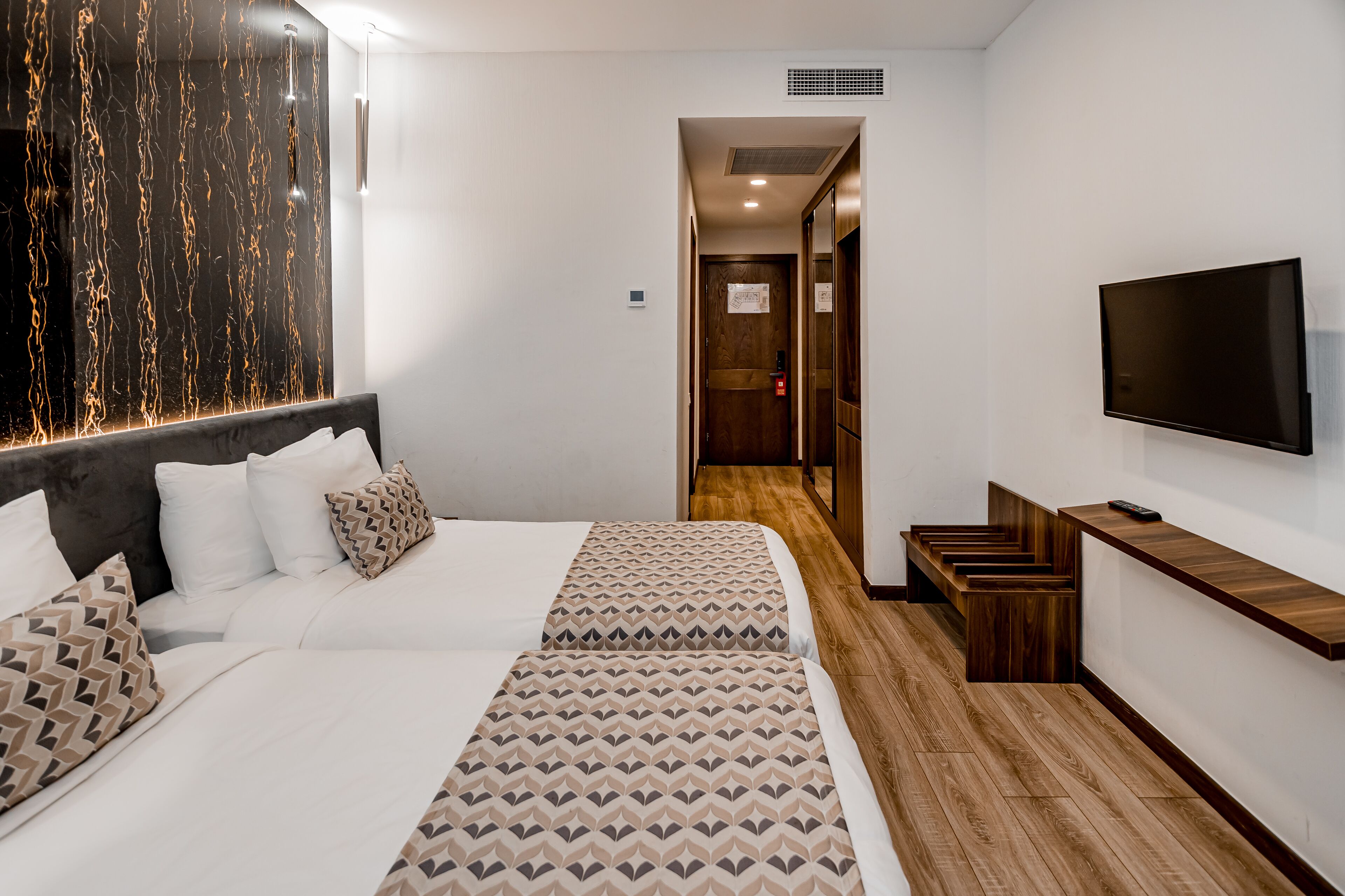 Una camera d'albergo con un letto, una TV e un pavimento in legno.