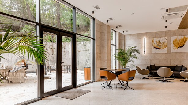 A spacious indoor area with a large glass door leading to an outdoor patio, furnished with modern chairs and a table. - Kutaisi Inn (Kutaisi)
