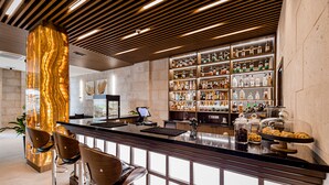 A modern bar area with a marble column, bar stools, and a well-stocked liquor shelf. - Kutaisi Inn (Kutaisi)