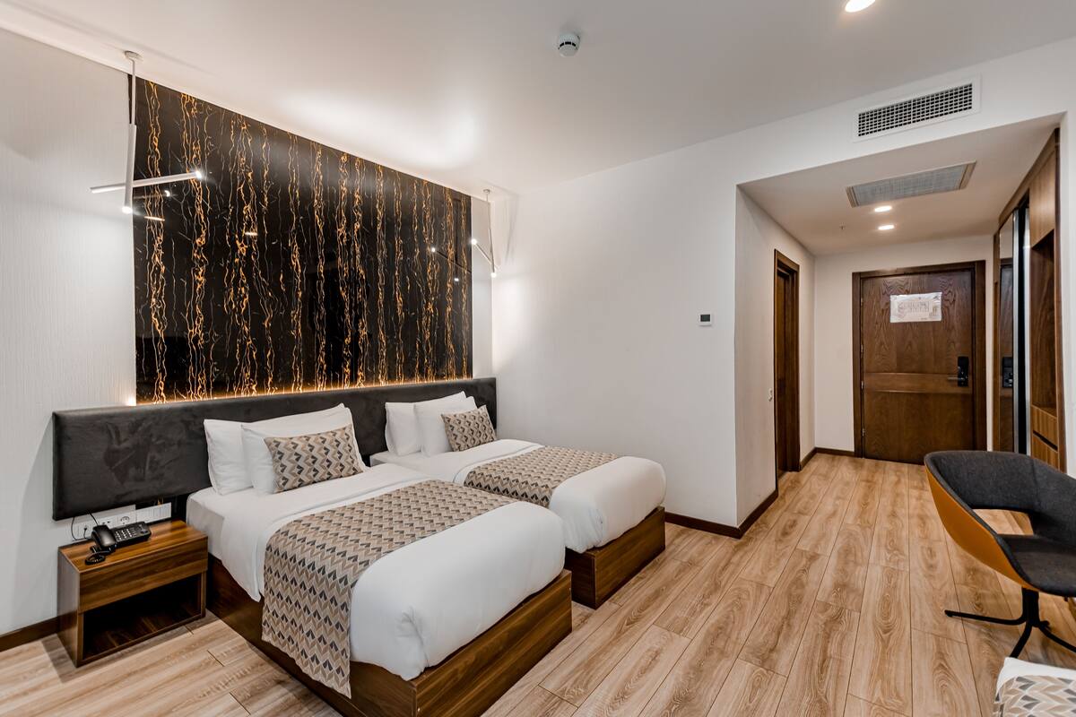 A hotel room with a large bed, bedside tables, a desk, and a chair.