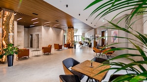 A spacious lobby with modern furniture, a wooden ceiling, and a large plant in the foreground. - Kutaisi Inn (Kutaisi)