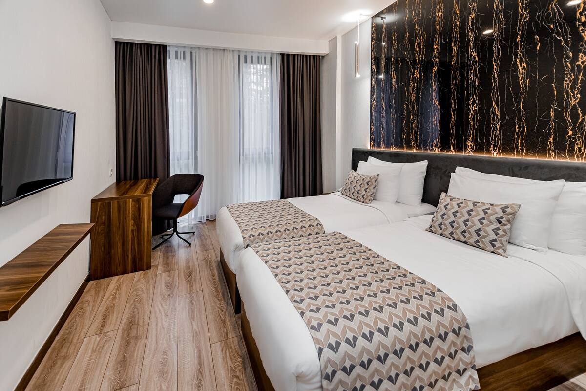 A modern hotel room with a large bed, a desk, and a TV.