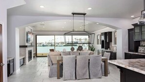 A spacious kitchen with a large island, a dining area with a view of the marina, and a modern ceiling design.