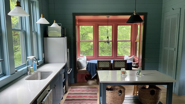 Ett kök med en fönsterplats, ett matbord och en köksö.
