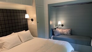 Ett sovrum med en stor säng, en mindre sittgrupp och två vägglampor.