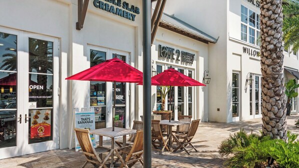 Une devanture de magasin avec une enseigne indiquant « Marble Slab Creamery » et « Love 2 Be ». On y trouve des tables et des chaises à l’extérieur, sous des parasols rouges.