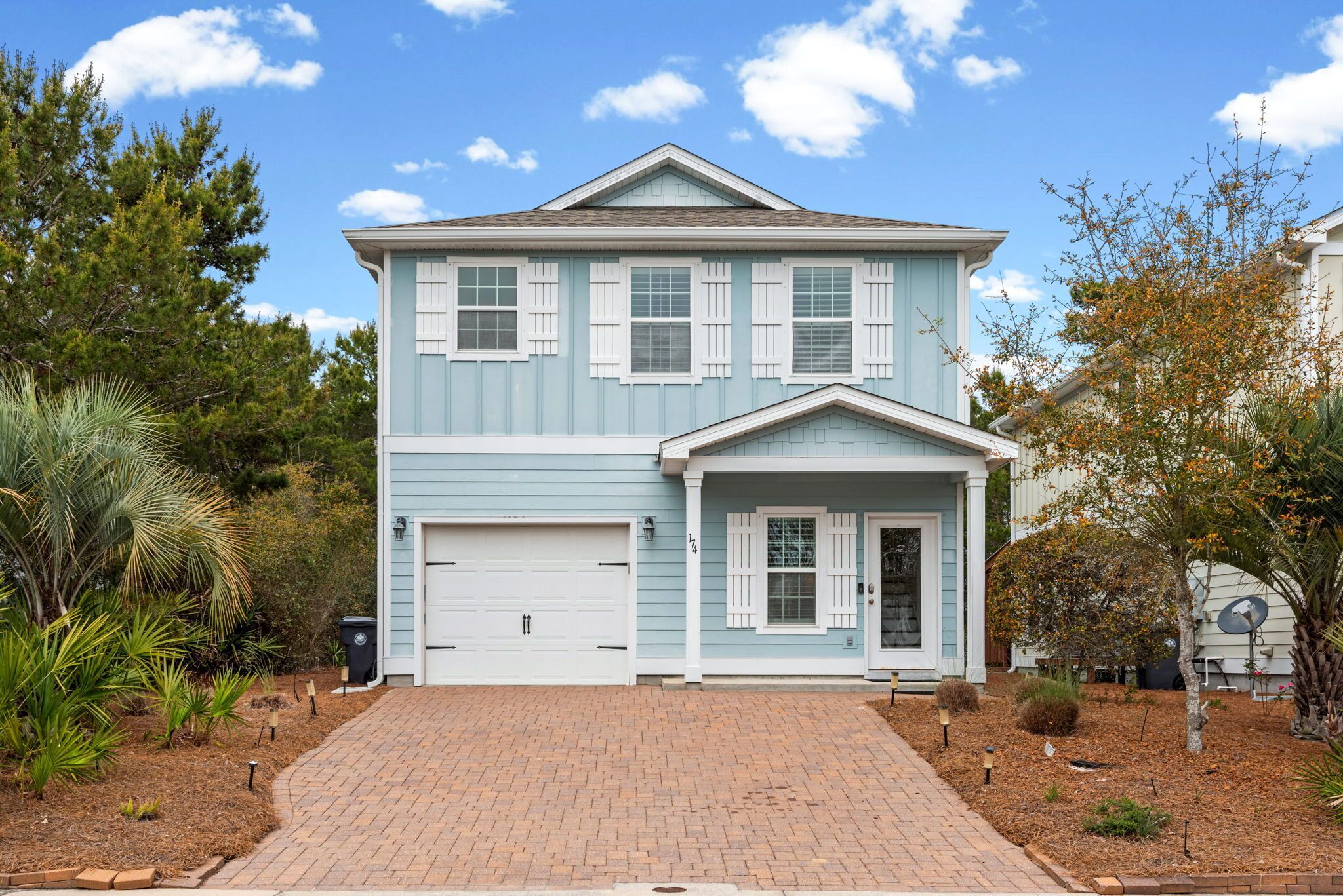 A two-story house with a garage, a front porch, and a brick driveway.