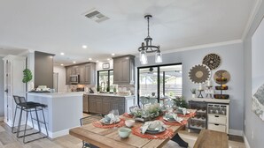 Una cocina moderna con una isla central, zona de bar y comedor.