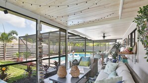 Un patio amplio con piscina, mobiliario exterior y vistas al jardín trasero.