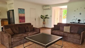 A living room with two brown sofas, a glass coffee table, and a kitchen in the background. - Villa Provencale Avec Piscine Privee (Sainte-Maxime)