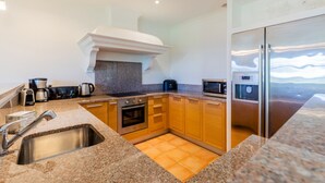 A modern kitchen with granite countertops, stainless steel appliances, and wooden cabinets. - Villa Provencale Avec Piscine Privee (Sainte-Maxime)