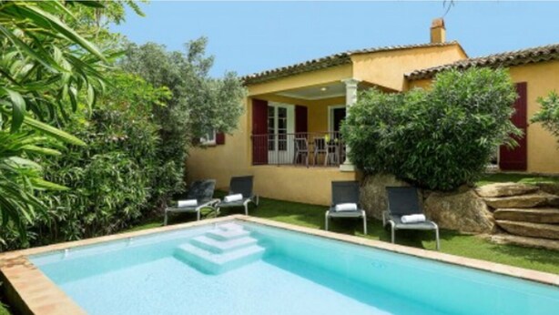 A poolside view of a yellow villa with a covered patio, surrounded by greenery and a stone staircase. - Villa Provencale Avec Piscine Privee (Sainte-Maxime)