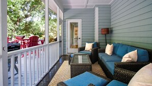 A covered porch with wicker furniture, a red table, and chairs. - Updated near beach home, outdoor paradise, sleeps 6! (Isle of Palms)