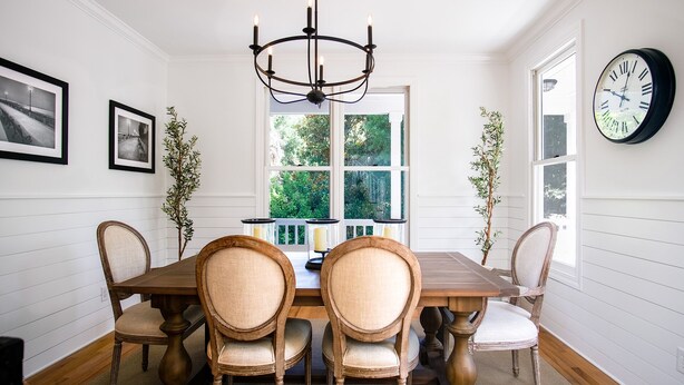 A dining room with a wooden table and four chairs, a chandelier, and a clock on the wall. - Updated near beach home, outdoor paradise, sleeps 6! (Isle of Palms)