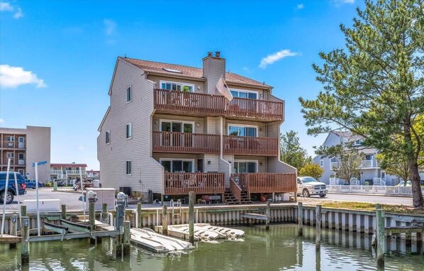 A multi-story building with a balcony, dock, and waterfront view.