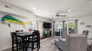 A dining area with a table and chairs, a ceiling fan, a TV, and a large fish decoration on the wall. - Large Ocean City Waterfront Townhome w/ Boat Slip (Ocean City)