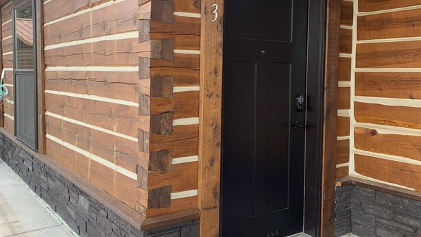 A log cabin-style building with a black door marked with the number 3. - {Big Timbers} Lodging next to North Entrance of Itasca State Park (Shevlin)