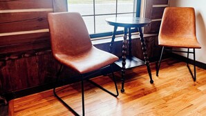 Two brown leather chairs and a small round table in a room with wooden floors and a large window. - {Big Timbers} Lodging next to North Entrance of Itasca State Park (Shevlin)