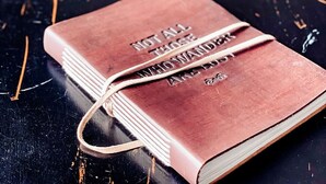 A book titled "Not All Those Who Wander Are Lost" on a black table. - {Big Timbers} Lodging next to North Entrance of Itasca State Park (Shevlin)
