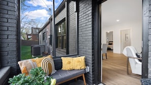 A modern interior with a bench by a large window, a white chair, and a visible kitchen area. - Lux living - Beautifully Renovated Home - Just 2 Miles from Downtown ATL (Atlanta)
