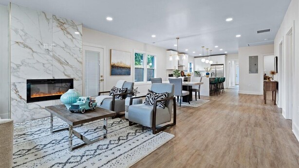 A spacious living room with a fireplace, comfortable seating, and a kitchen in the background. - Lux living - Beautifully Renovated Home - Just 2 Miles from Downtown ATL (Atlanta)