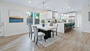 A modern kitchen with white cabinets, a central island, and pendant lighting. - Lux living - Beautifully Renovated Home - Just 2 Miles from Downtown ATL (Atlanta)