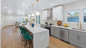 A modern kitchen with a central island, stainless steel appliances, and pendant lighting. - Lux living - Beautifully Renovated Home - Just 2 Miles from Downtown ATL (Atlanta)