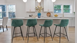 A modern kitchen with white cabinets, a central island with bar stools, pendant lighting, and a view of the outdoors. - Lux living - Beautifully Renovated Home - Just 2 Miles from Downtown ATL (Atlanta)