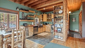 Una cocina rústica con gabinetes de madera, lavavajillas y un comedor con sillas de madera.