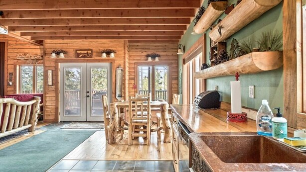 Un interior de madera con zona de comedor, encimera de cocina y chimenea.