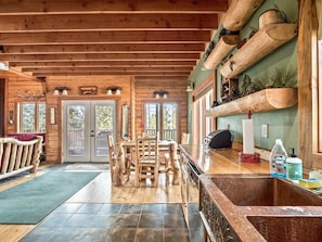 Um interior em madeira com área de refeições, bancada de cozinha e lareira.