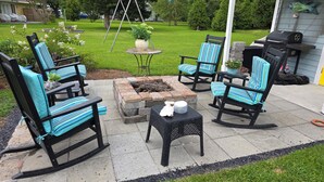Terrassenmöbel im Freien mit Stühlen und Tisch, einem Feuerkorb und einem Grill.