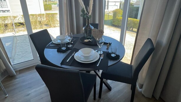 A dining area with a table set for four, large windows, and a view of the outside.