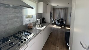 A modern kitchen with a gas stove, a window, and a dining area with a table and chairs.