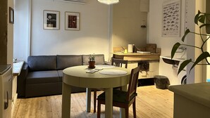 A compact living space with a dining table, a sofa, a small kitchen area, and a wall-mounted air conditioner. - Old Town Apartment (Cēsis)