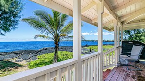 A covered outdoor area with a view of the ocean, a grill, and a seating area. - Temple Tree Retreat: An Adventurer's Oceanfront Paradise! (Keaau)
