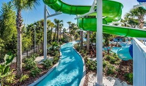 Ein Wasserpark mit mehreren Rutschen, einem gewundenen Pool und Palmen.