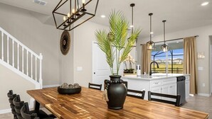 A modern kitchen with a wooden dining table, black chairs, and a large vase with greenery. - 🌺 Aloha Oasis | Private Pool • Windsor Island • Near Disney (Davenport)