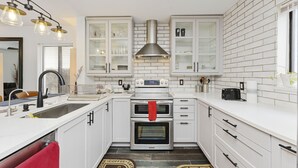 Una cocina moderna con armarios blancos, electrodomésticos de acero inoxidable y un salpicadero blanco y negro.