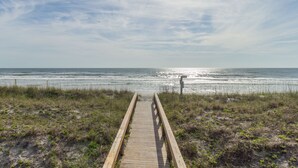 Una pasarela de madera que conduce a la playa, con una vista despejada del océano.