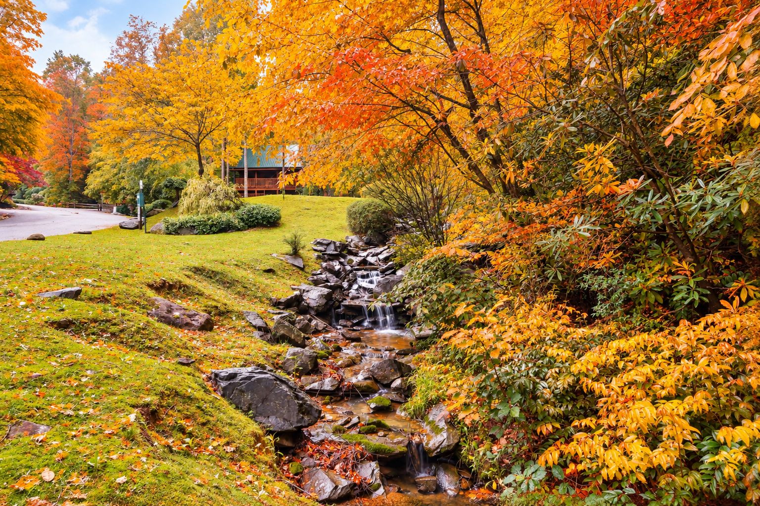 A serene garden with a small waterfall, lush greenery, and a wooden structure in the background.