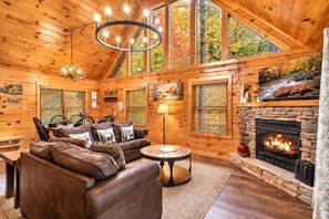 A cozy cabin interior with a stone fireplace, wooden walls, and a leather sofa.