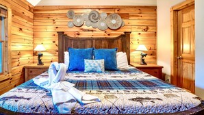 Ein gemütliches Schlafzimmer mit einem Holzkopfteil, einem Bett mit blau-weißer Bettwäsche und zwei Nachttischen mit Lampen.