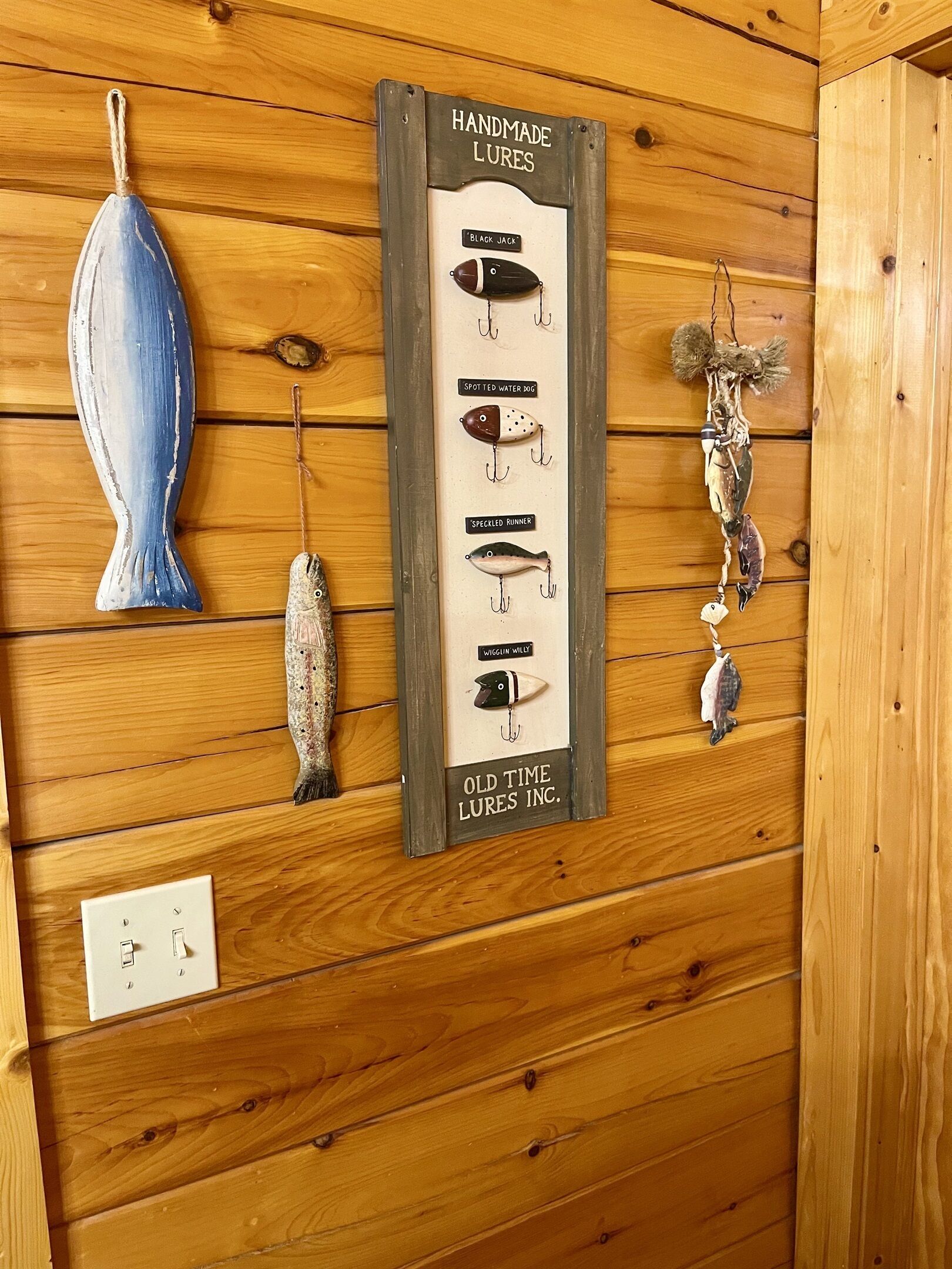 A wooden wall with a lures display and a blue vase.