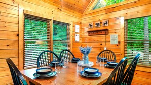 Ein Esszimmer einer Holzhütte mit einem Holztisch, gedeckt für sechs Personen, umgeben von Stühlen.
