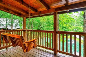 Un pontile di legno con un'altalena, una ringhiera e vista su un lago circondato da alberi.
