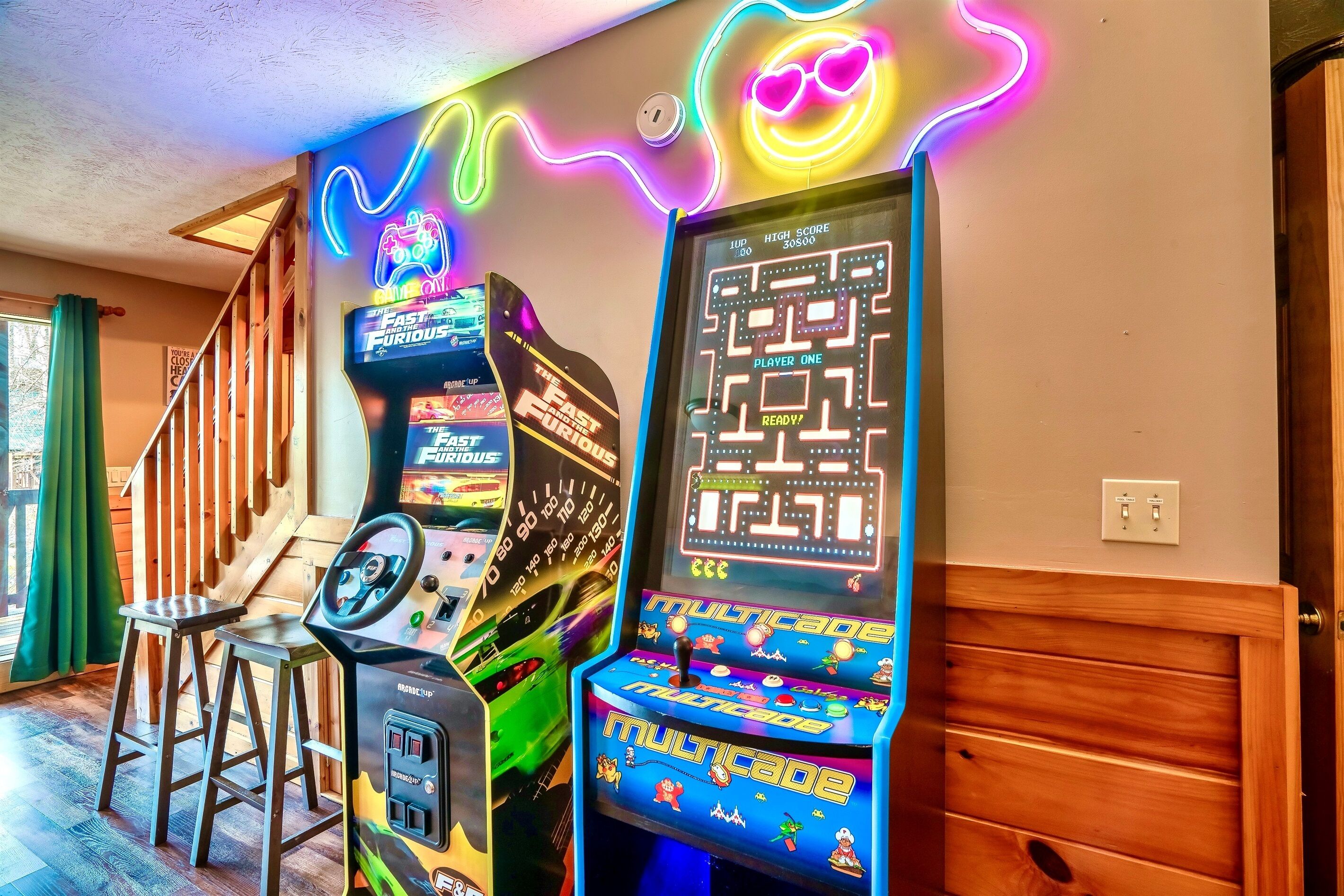 Ein Raum mit Spielautomaten, einer Holztreppe und einem Neonlicht.
