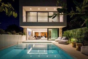 Una casa moderna de dos pisos con piscina, balcón e interior luminoso.
