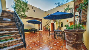 A courtyard with a wooden staircase, outdoor seating, and potted plants. - Hotel Casa Tequis San Luis Potosi (San Luis Potosi)